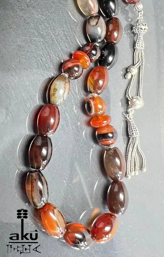 Naturachat Tasbih mit 925er Silberquaste, zeigt polierte Perlen in Brauntönen und feine Silberdetails.
