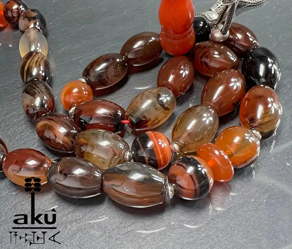Naturachat Tasbih mit 925er Silberquaste, zeigt polierte Perlen in Brauntönen und feine Silberdetails.