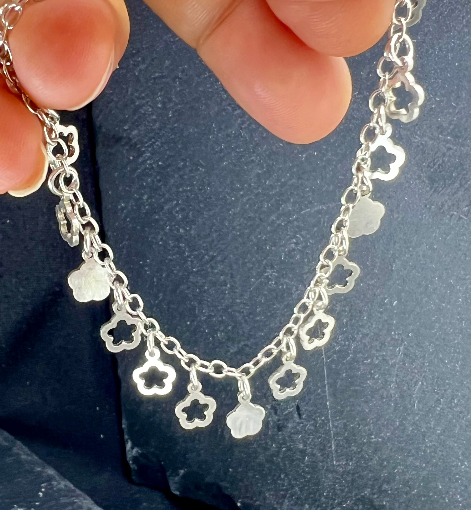 Nahaufnahme eines Vintage-Armbands aus 925 Silber mit Blümchen-Anhängern, filigraner Kette und Design aus den 1980er Jahren.
