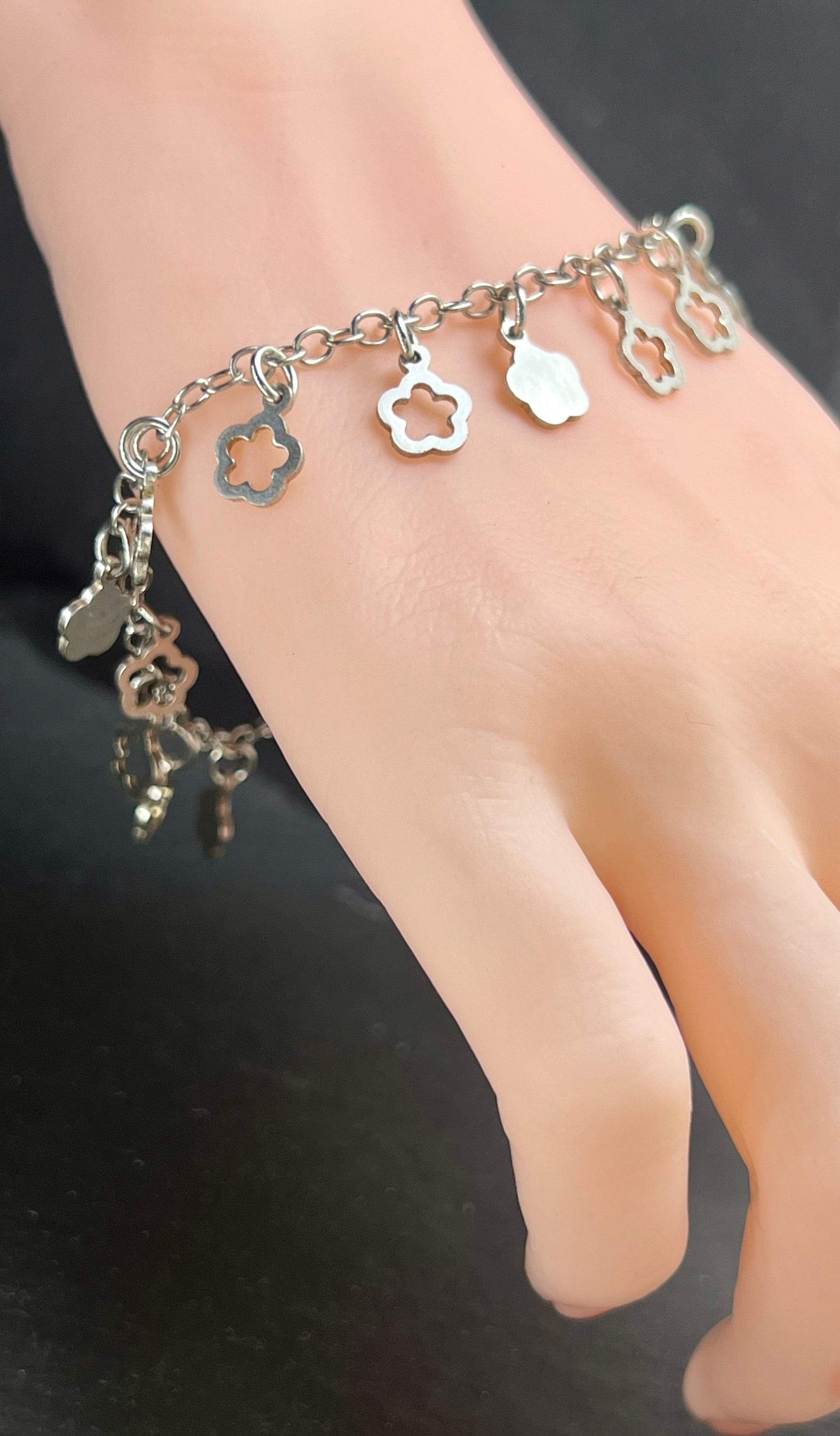 Nahaufnahme eines Vintage-Armbands aus Silber mit Blümchen-Anhängern, filigraner Kette und Design aus den 1980er Jahren.