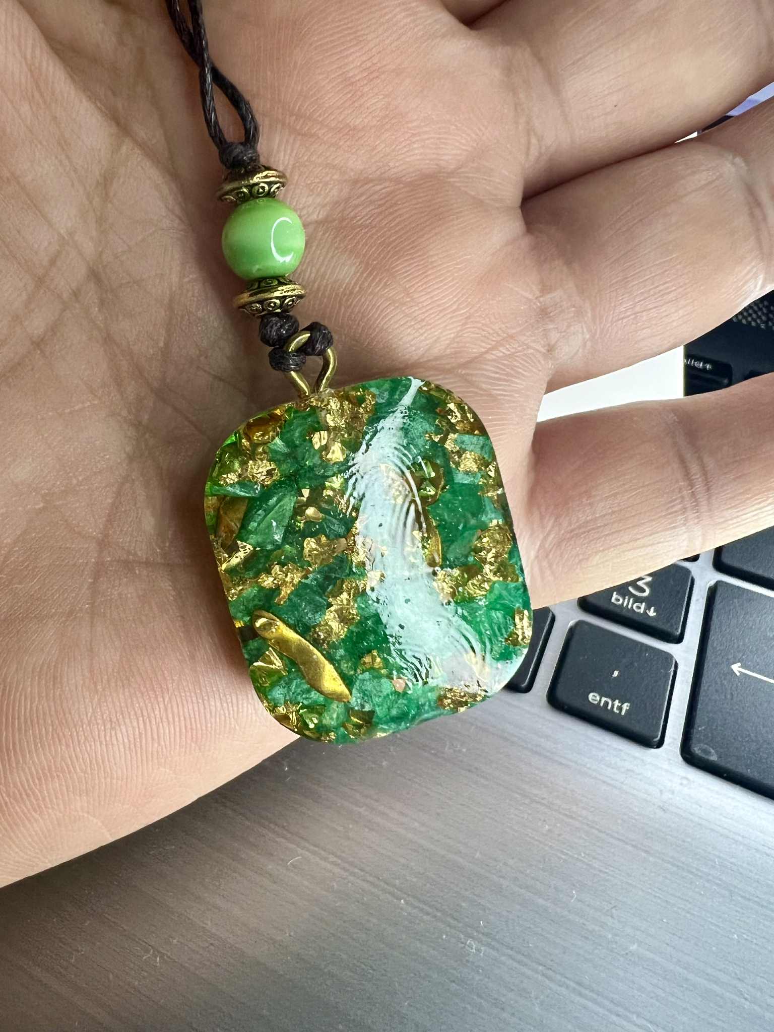 Anhänger Halskette aus grünem Kunstharz mit goldfarbenen Einlagen und einem filigranen Lebensbaum-Motiv. Der Baum des Lebens