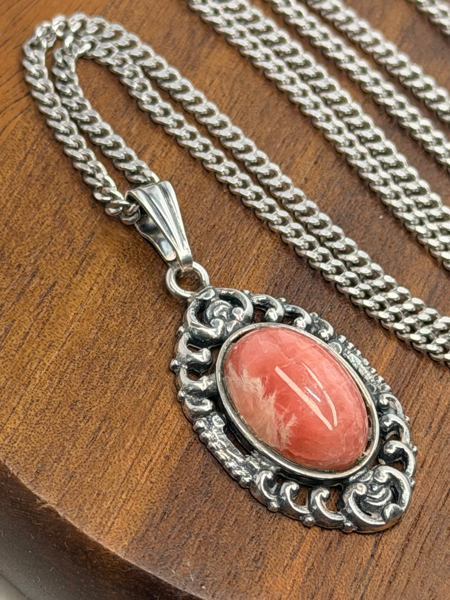 Vintage Rhodochrosit Anhänger Kette – Elegantes, verziertes Silber, Klassische Eleganz auf Holz