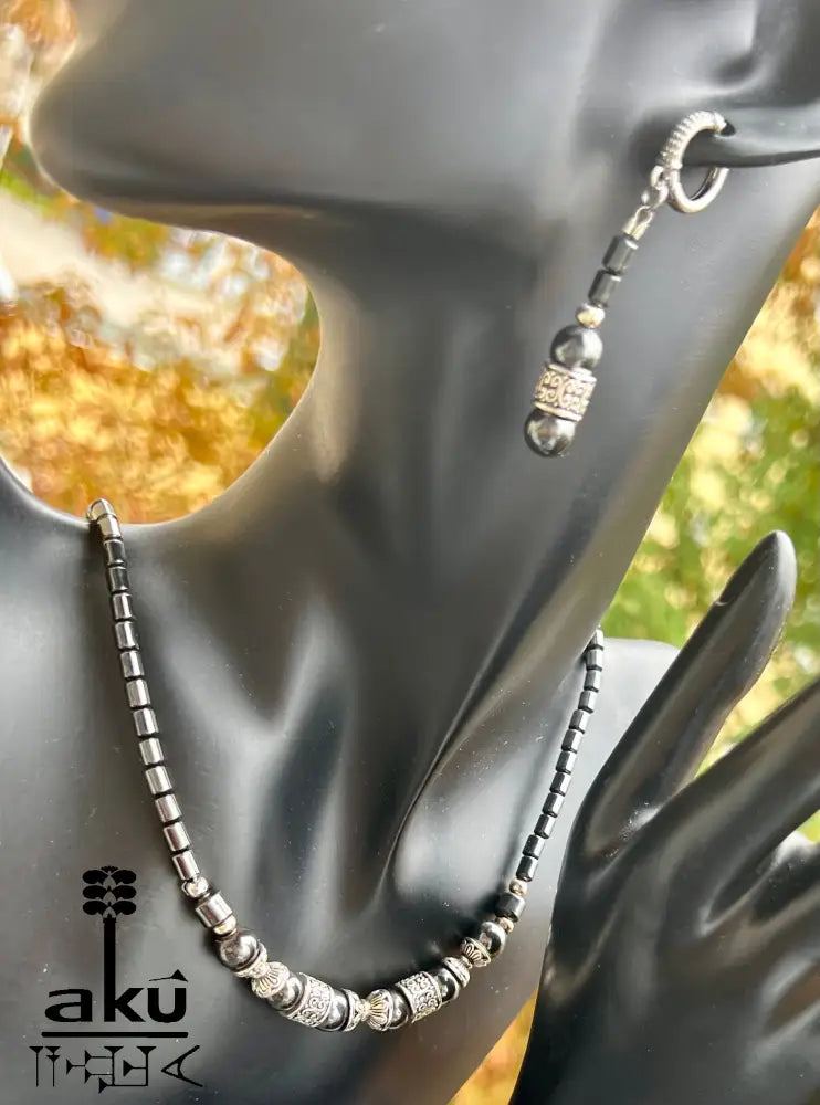 Halskette, Armband und Ohrringe aus magnetischem Hämatit, präsentiert auf schwarzem Schmuckdisplay.