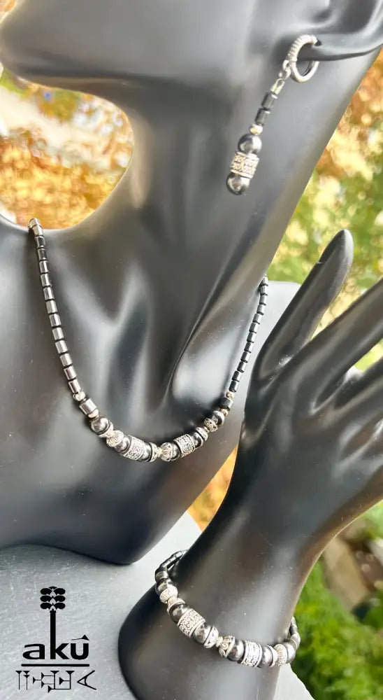 Halskette, Armband und Ohrringe aus magnetischem Hämatit, präsentiert auf schwarzem Schmuckdisplay.