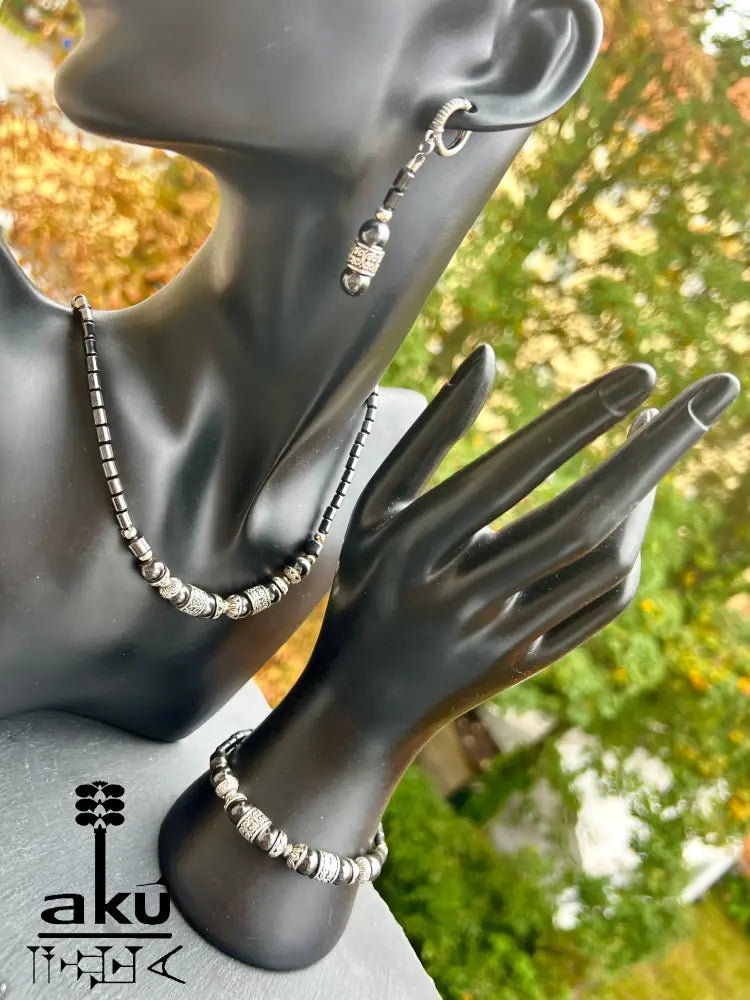 Halskette, Armband und Ohrringe aus magnetischem Hämatit, präsentiert auf schwarzem Schmuckdisplay.