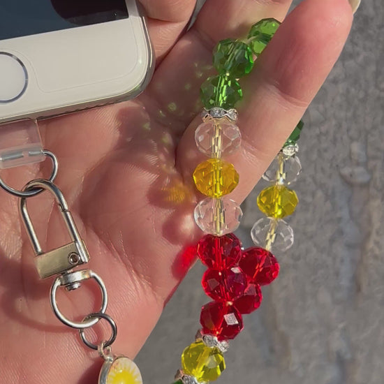 Handykette aus glänzenden Kristale Glasperlen&nbsp;in Form eines kleinen Gebetskranzes vereint ein verspieltes Design mit einer kleinen Flaggenmedaille.