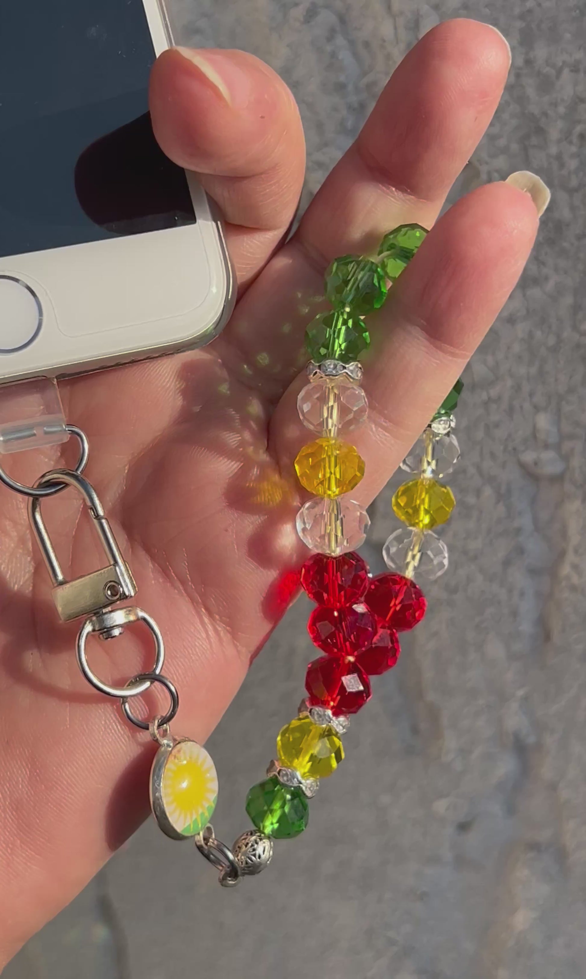 Handykette aus glänzenden Kristale Glasperlen&nbsp;in Form eines kleinen Gebetskranzes vereint ein verspieltes Design mit einer kleinen Flaggenmedaille.