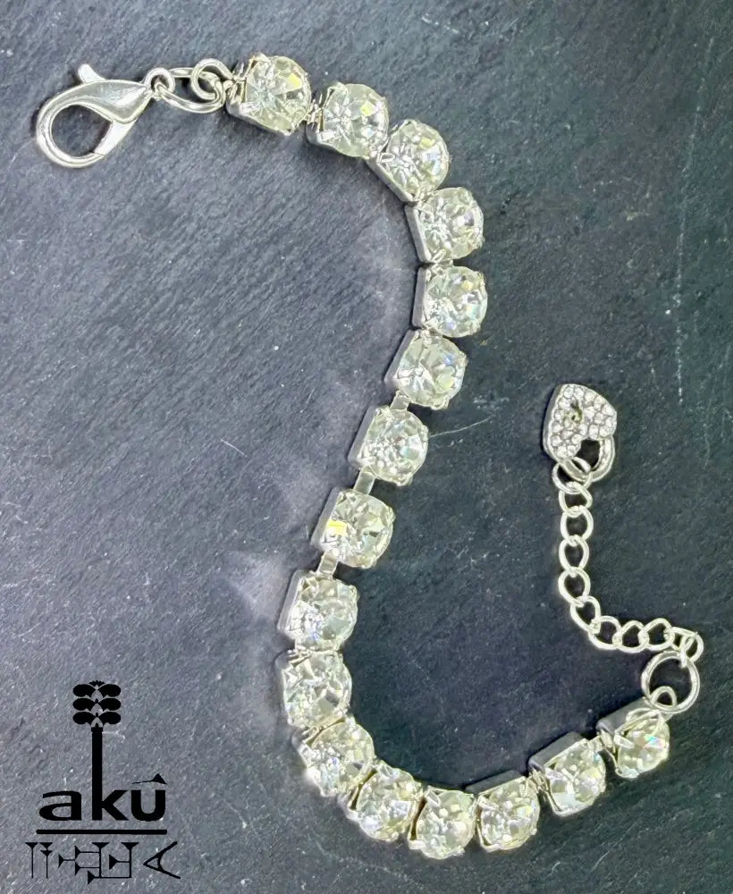 Strasssteinen einreihiges Armband, auf dunklem Hintergrund. Nahaufnahme der Herz-Charms und Karabinerverschlüsse