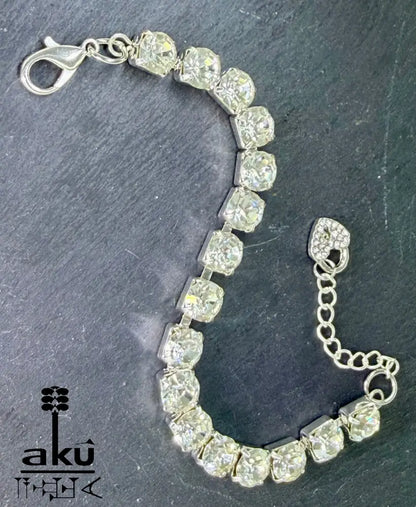 Strasssteinen einreihiges Armband, auf dunklem Hintergrund. Nahaufnahme der Herz-Charms und Karabinerverschlüsse