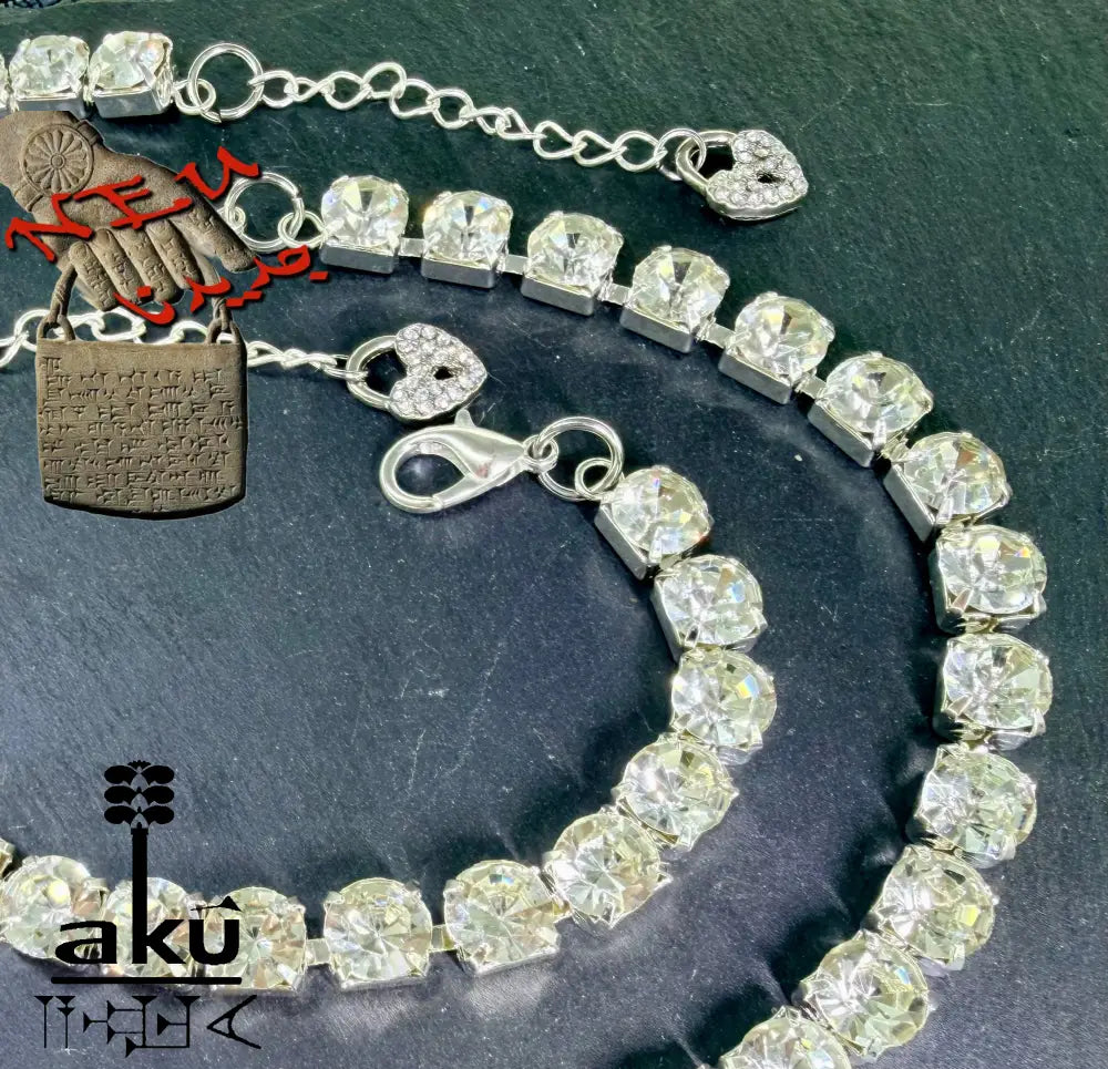 Tennis-Schmuckset mit Strasssteinen auf dunklem Hintergrund. Nahaufnahme der Herz-Charms und Karabinerverschlüsse