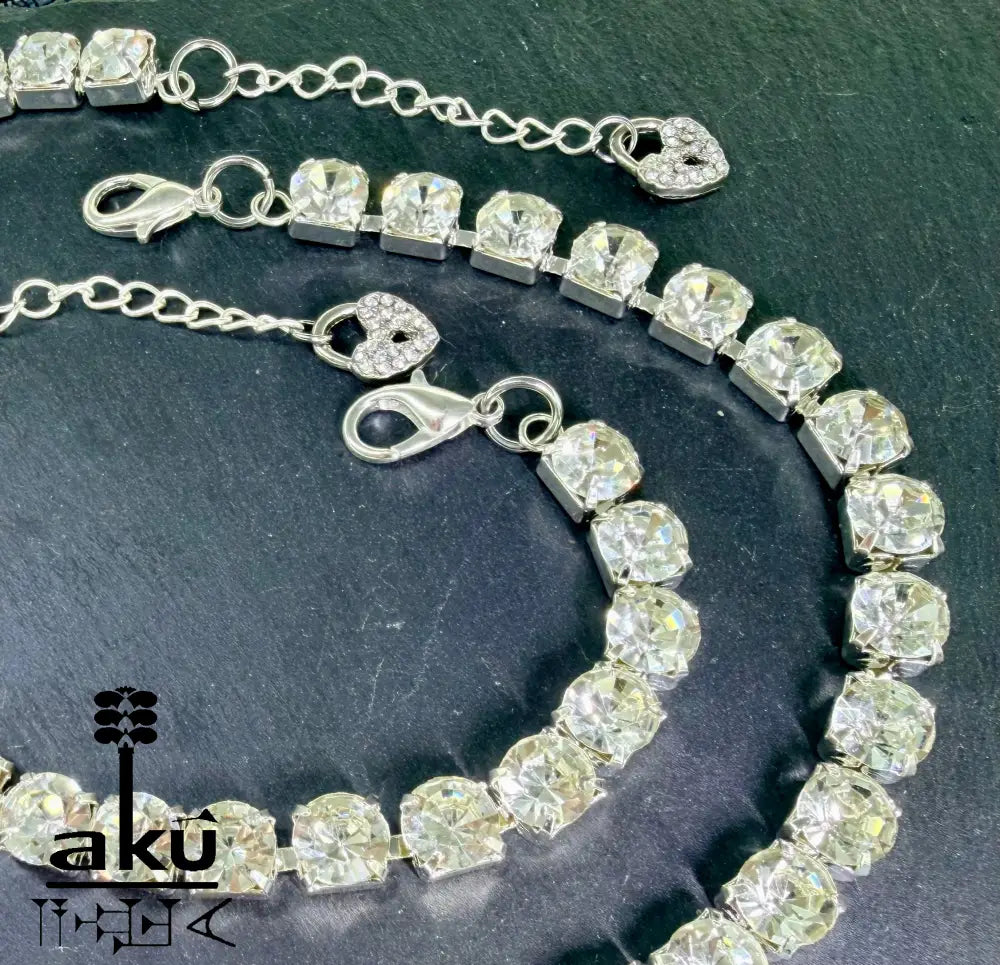 Tennis-Schmuckset mit Strasssteinen auf dunklem Hintergrund. Nahaufnahme der Herz-Charms und Karabinerverschlüsse