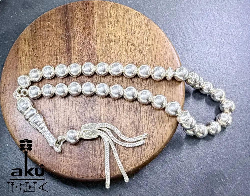 Flach ausgelegter Tasbih mit sichtbarer Perlenstruktur und geflochtenem Quast