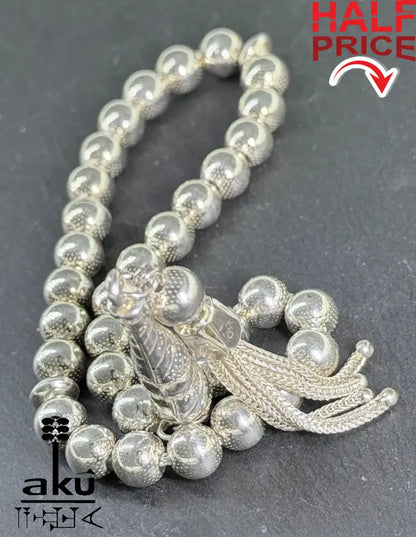 Sterlingsilber-Tasbih mit 33 strukturierten Perlen und Quast auf dunklem Hintergrund