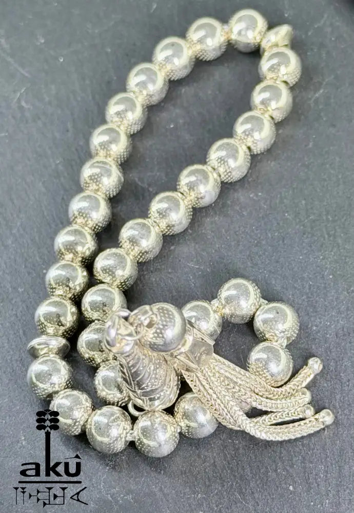 Flach ausgelegter Tasbih mit sichtbarer Perlenstruktur und geflochtenem Quast