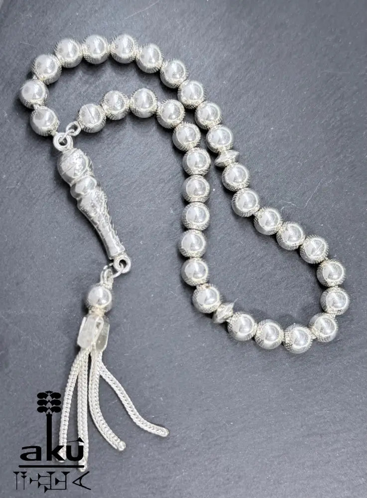 Flach ausgelegter Tasbih mit sichtbarer Perlenstruktur und geflochtenem Quast