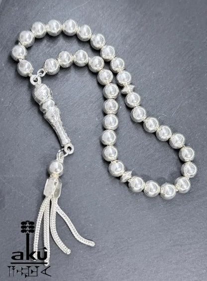 Flach ausgelegter Tasbih mit sichtbarer Perlenstruktur und geflochtenem Quast