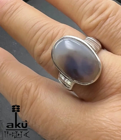 Hand mit Silberring, Stein zeigt dunkle Silhouetten